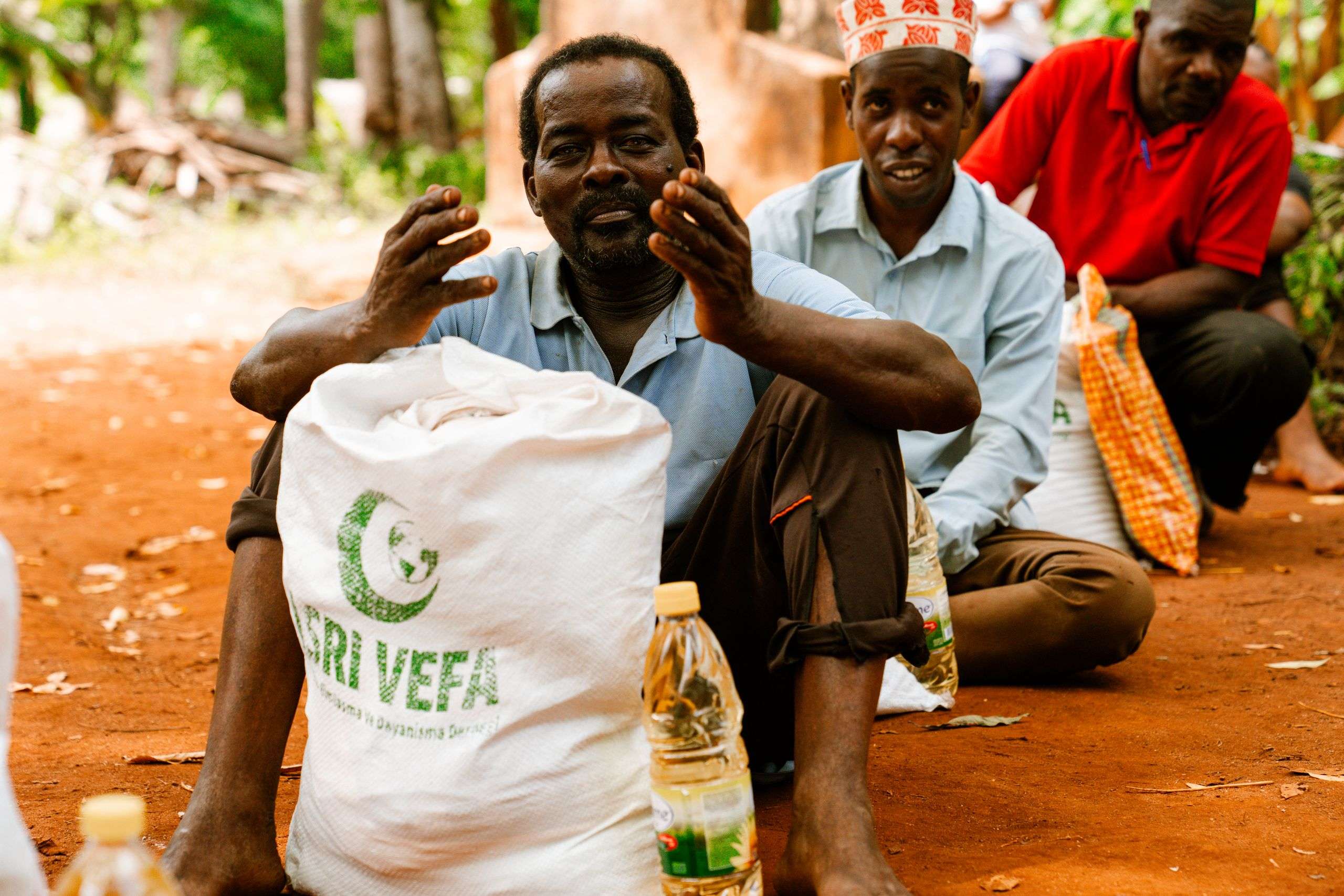 Group of men gathered with food supplies in a rural outdoor setting