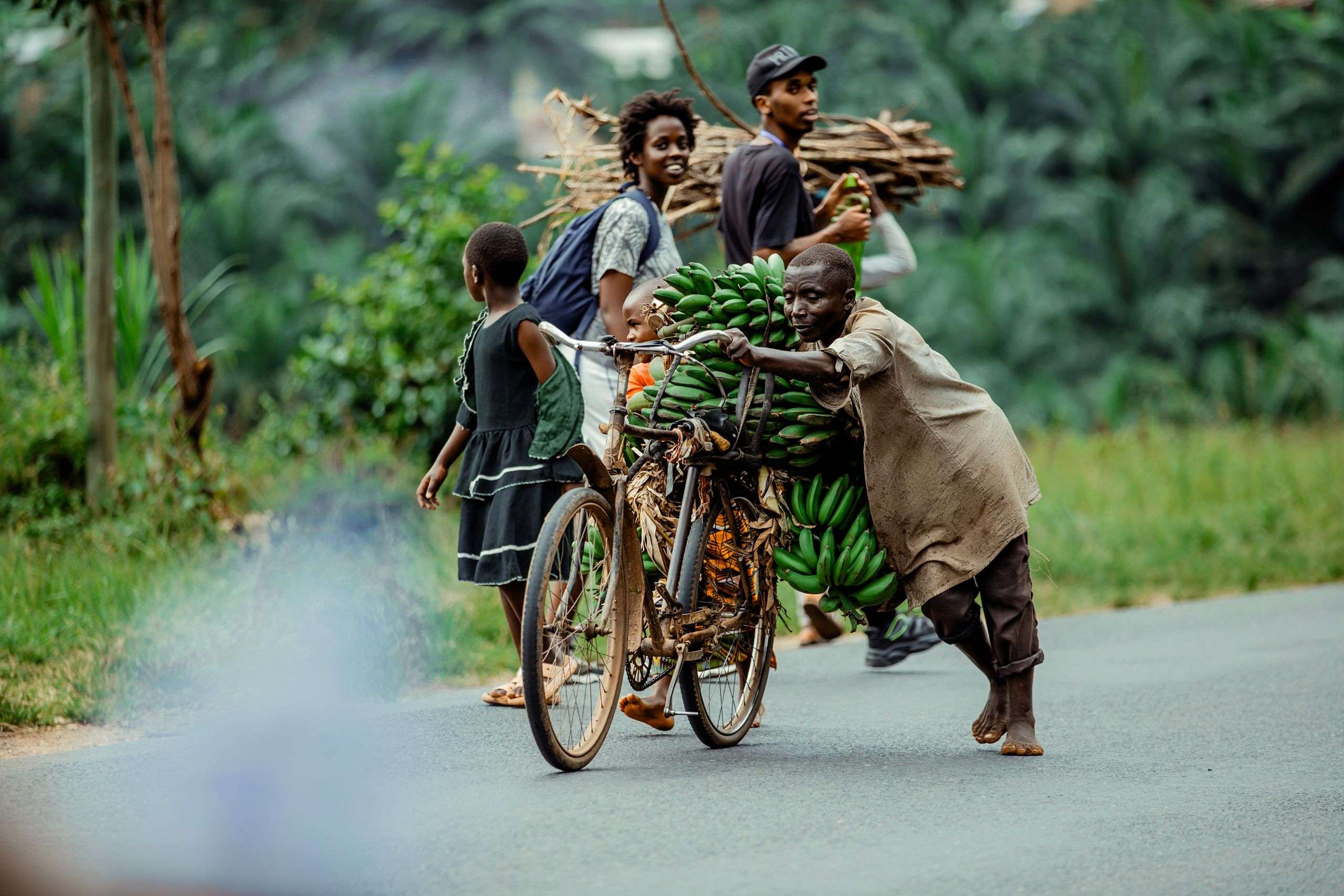 Villagers carrying bananas along a rural road