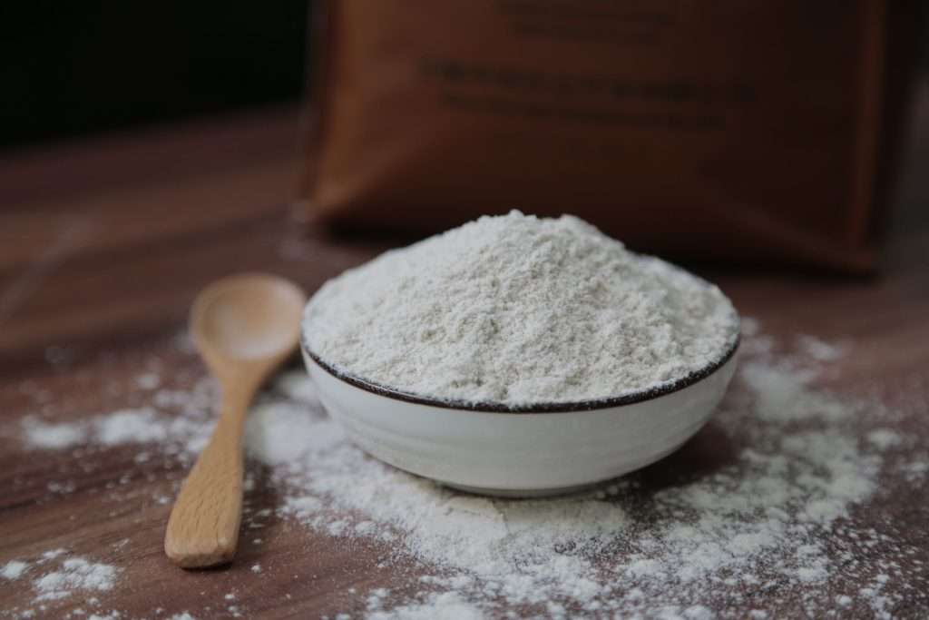 Fine flour in a ceramic bowl with a wooden spoon