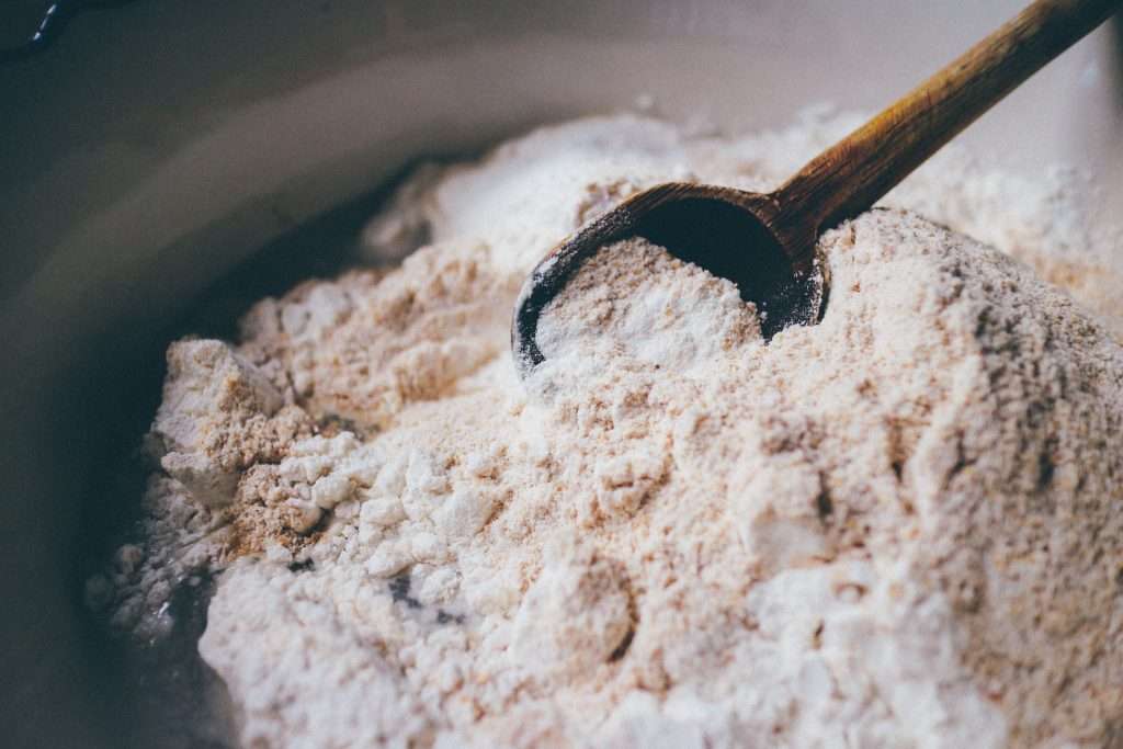 Wooden spoon resting in a mound of milled flour