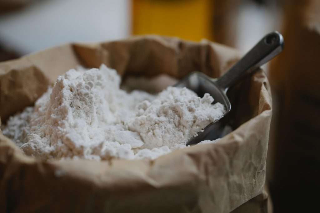 Paper bag of flour with a steel scoop